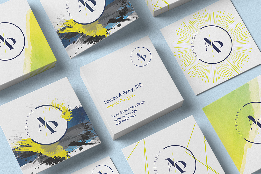 Business cards laid out in a grid, alternating navy paint-splatter backs with white fronts carrying the monogram and contact details