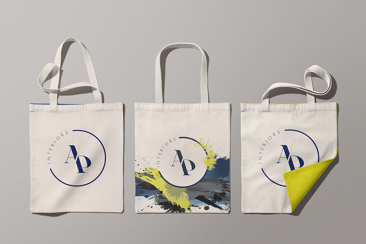 Three canvas tote bags printed with the monogram, one folded back to reveal a chartreuse lining