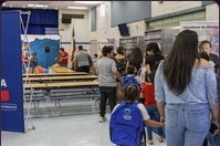 Attendees crossing the cafeteria floor with backpacks, a firm banner behind them