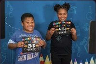 Two children holding first-day-of-school signs in front of the photo backdrop