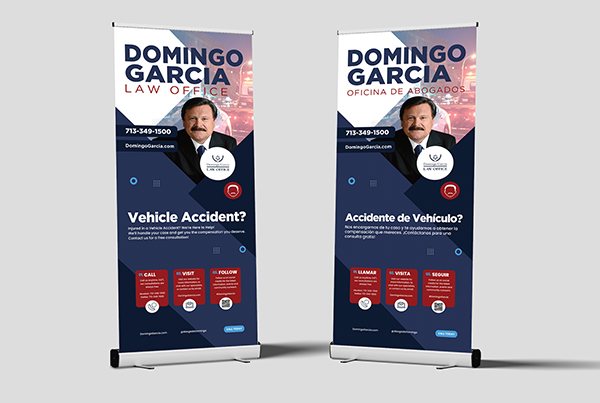 Two retractable banner stands for the firm, one in English reading 'Vehicle Accident?' and one in Spanish reading 'Accidente de Vehiculo?', each carrying the attorney's portrait and contact details